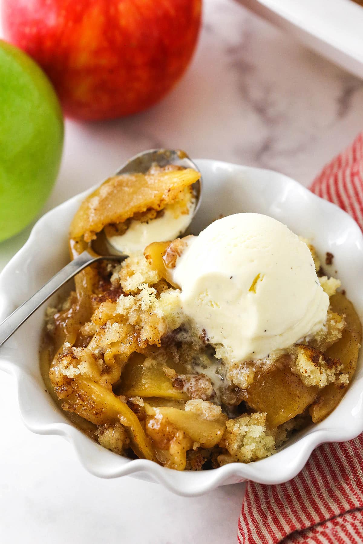 A bowl of apple cobbler topped with a scoop of vanilla bean ice cream