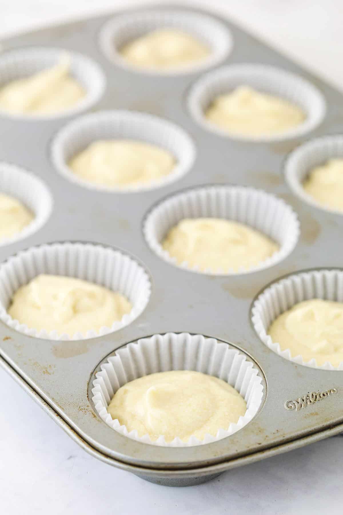 Overhead view of batter added to cupcake pan with cupcake liners