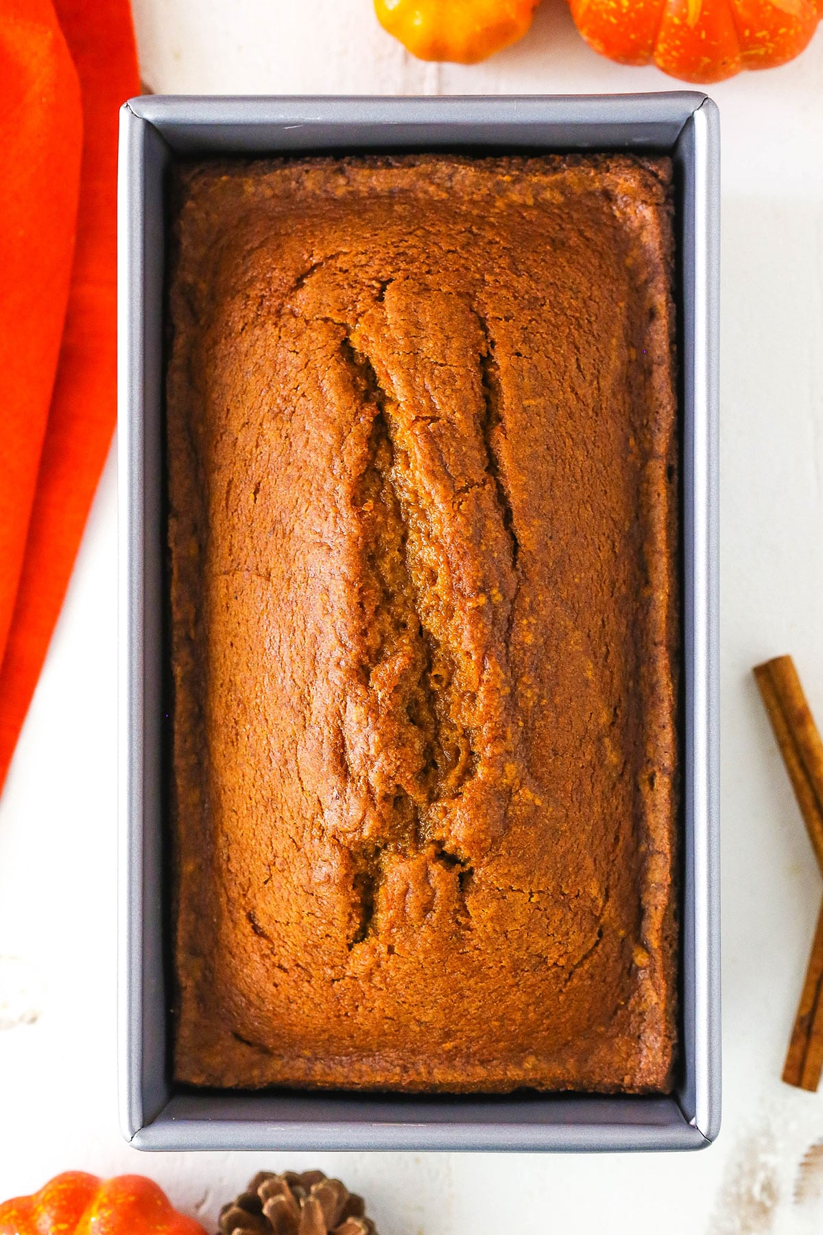 Overhead view of a full loaf of Pumpkin Bread in a metal baking pan on a white table