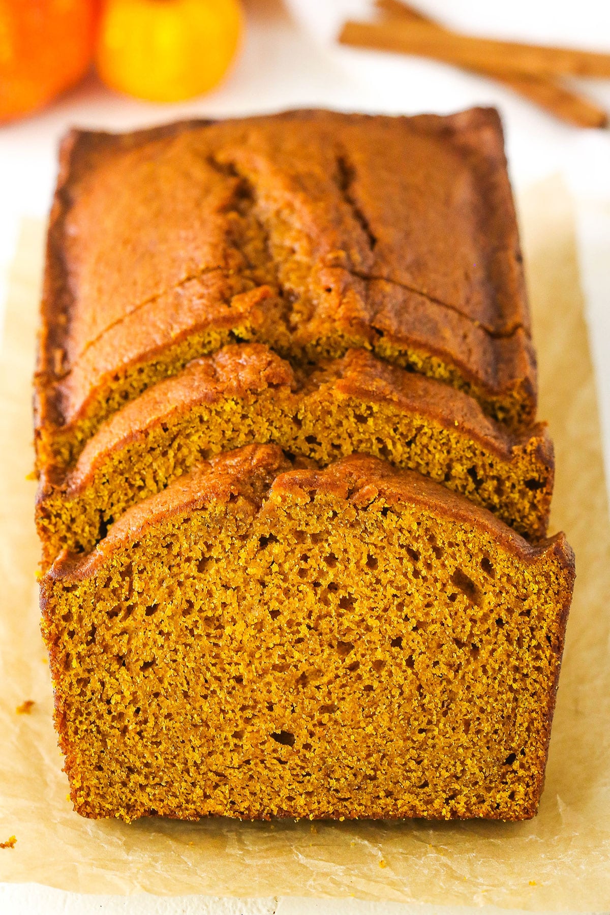 Side view of three slices of Pumpkin Bread leaning against the remainder of the Pumpkin Bread loaf