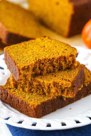 Two halves of Pumpkin Bread on top of another slice of Pumpkin Bread on a white plate