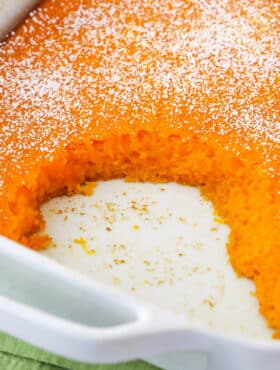A carrot souffle in a casserole dish with a few servings missing