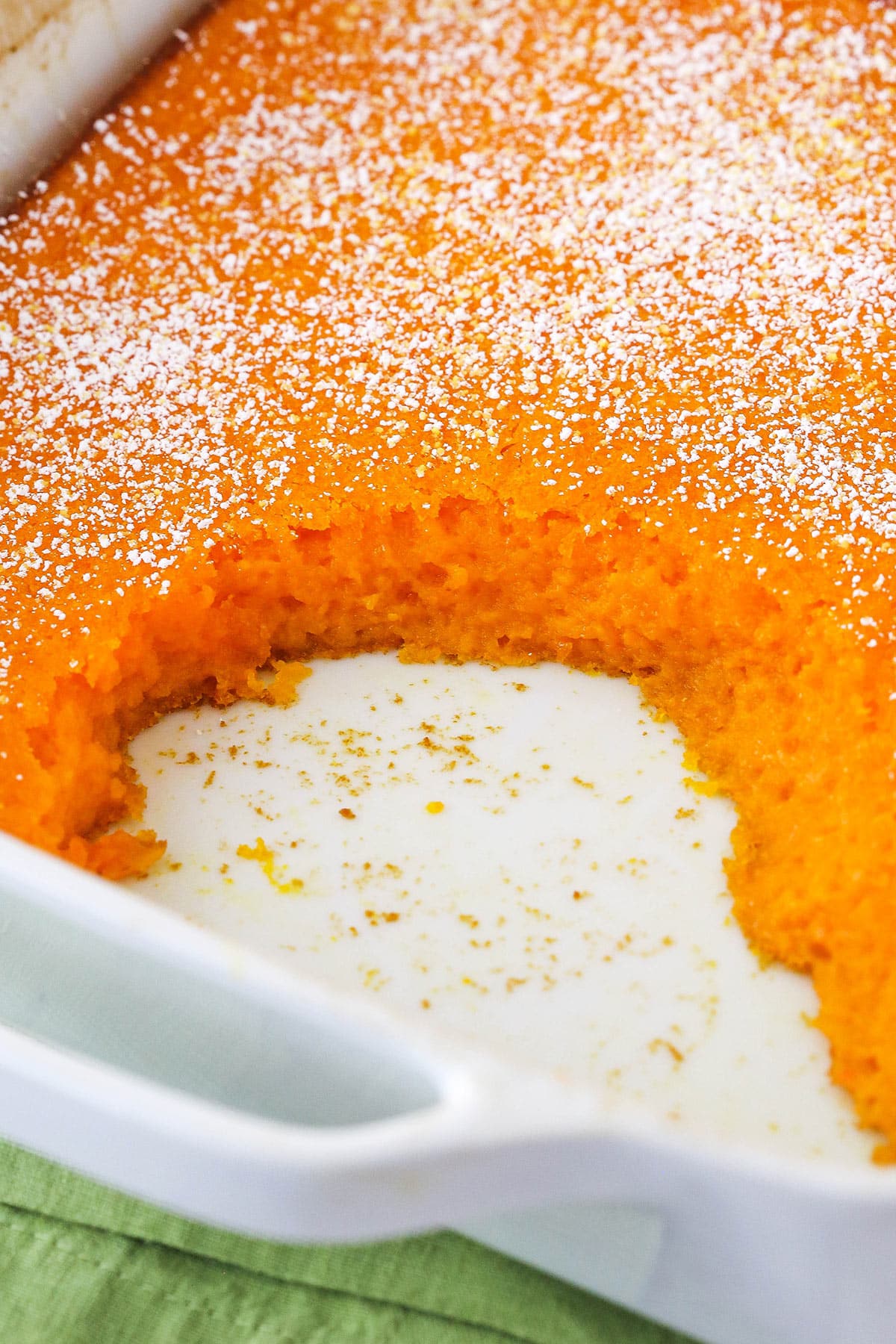 A carrot souffle in a casserole dish with a few servings missing