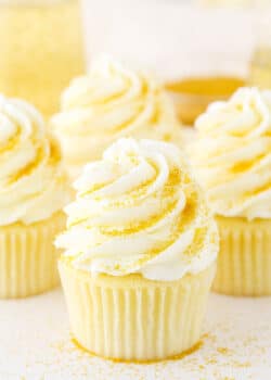 Four Champagne Cupcakes decorated with buttercream frosting on a white table top