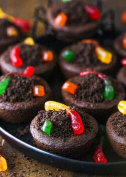 Chocolate cookies stuffed with buttercream frosting, covered with Oreo crumbs and topped with gummy worms