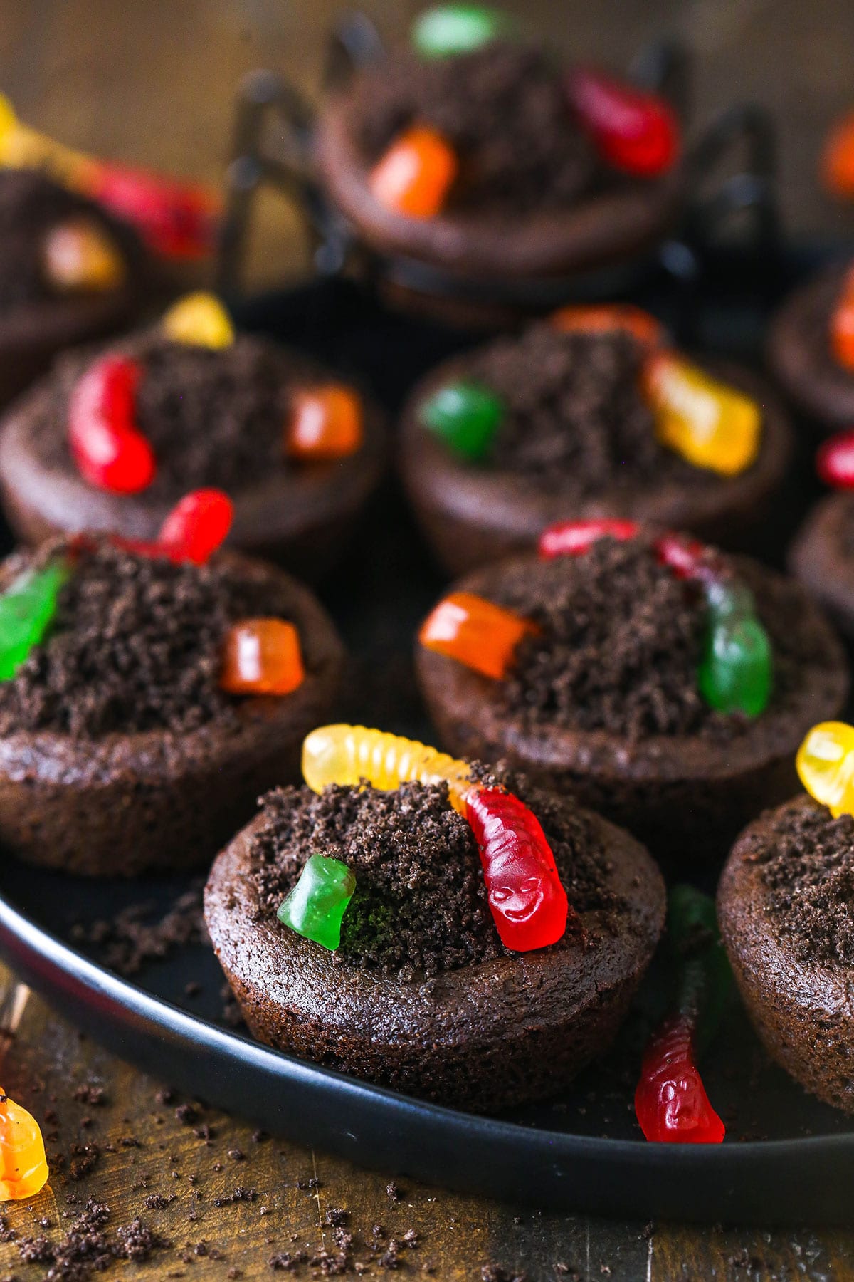 Chocolate cookies stuffed with buttercream frosting, covered with Oreo crumbs and topped with gummy worms