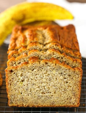 Side view of three Banana Bread slices leaning against the remaining banana bread loaf on a cooling rack