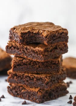 A stack of homemade brownies. The top one has a bite taken out of it.