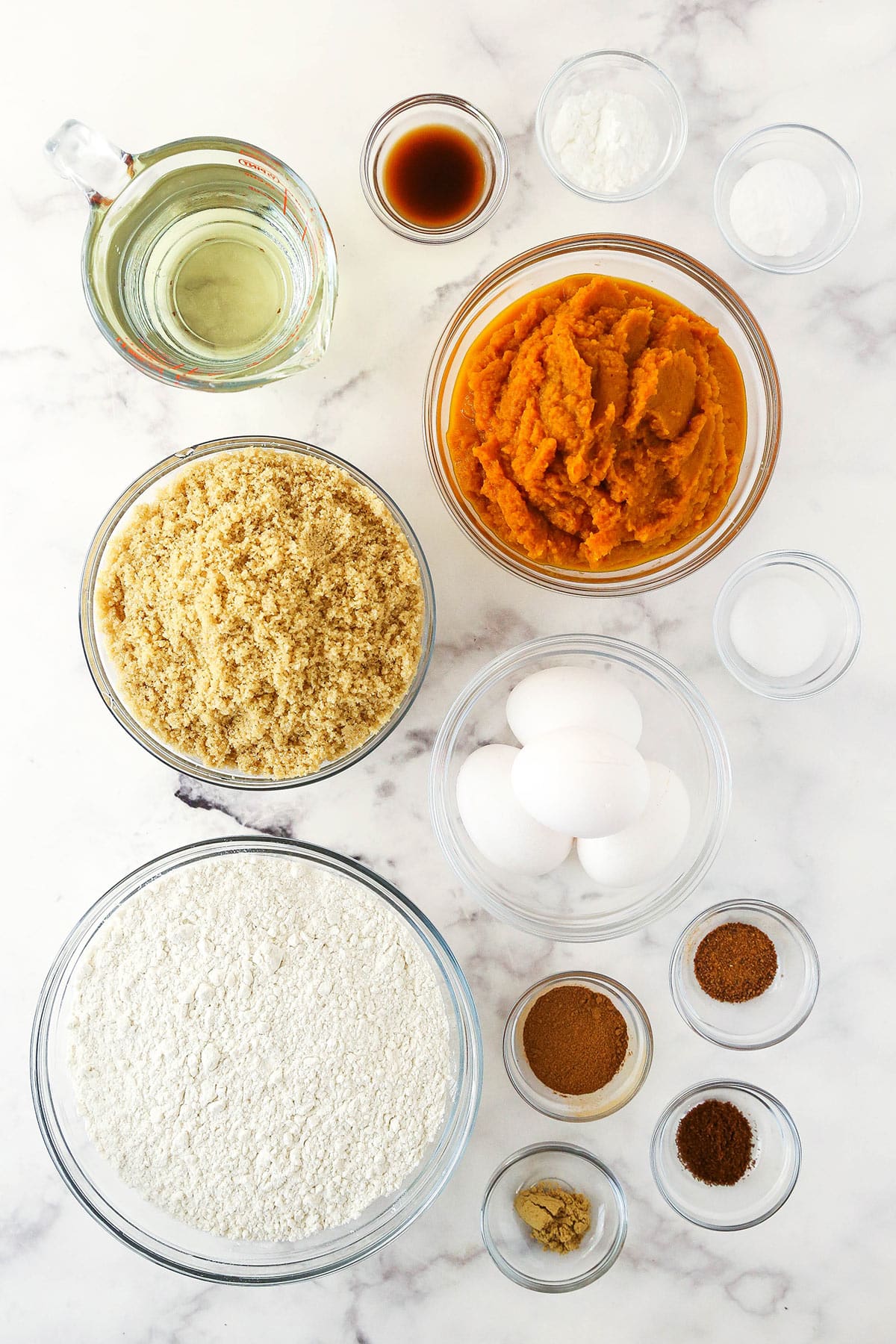 Eggs, cinnamon, nutmeg, ginger and the rest of the ingredients arranged neatly on a kitchen countertop.