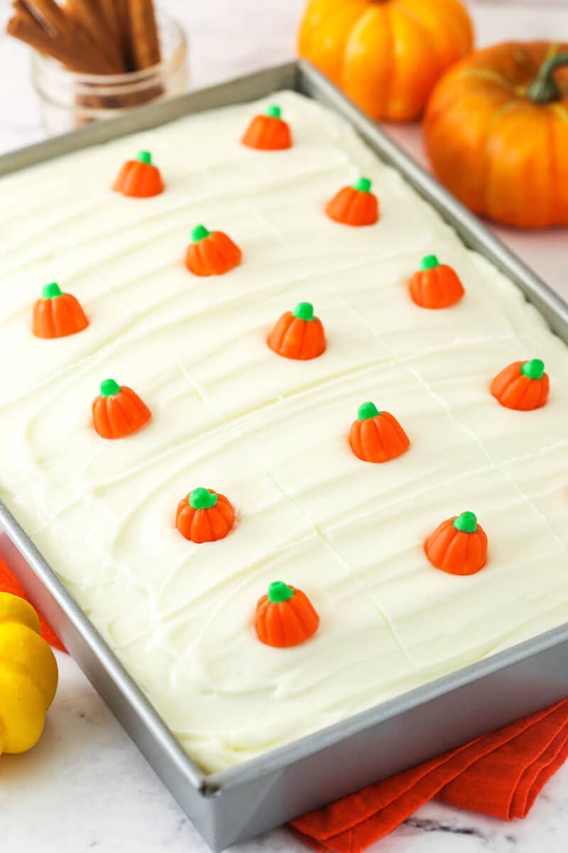 Pumpkin cake frosted with cream cheese frosting and decorated with mini pumpkin candies.