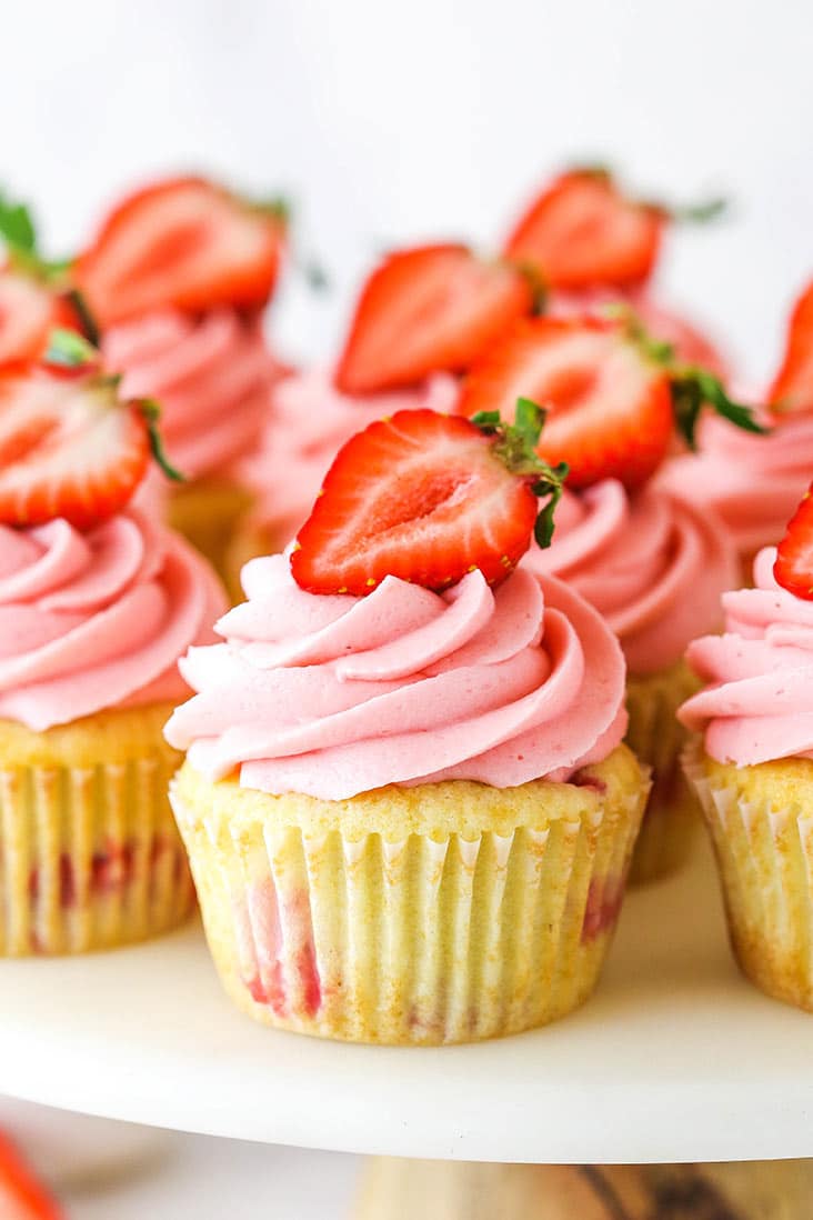 strawberry cupcake on a cake stand with other cupcakes around