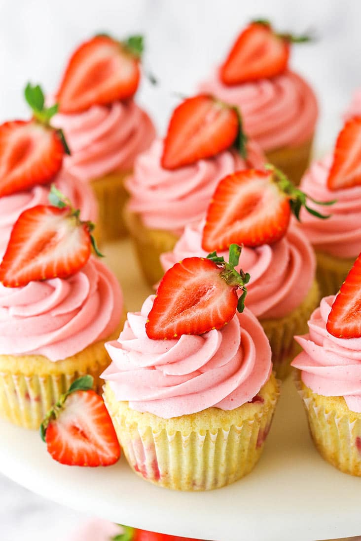 bunch of strawberry cupcakes on the top of a cake stand