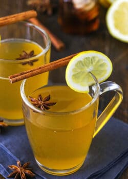 Two Cups of Hot Toddy Garnished with a Lemon Slice, a Cinnamon Stick and an Anise Star