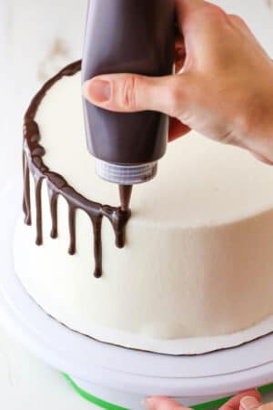 How to Make a Chocolate Drip Cake tutorial showing using a squeeze bottle to drip chocolate ganache down the sides of a cake