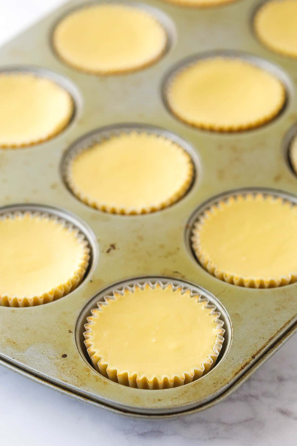 Mini caramel cheesecakes cooling in a cupcake pan.