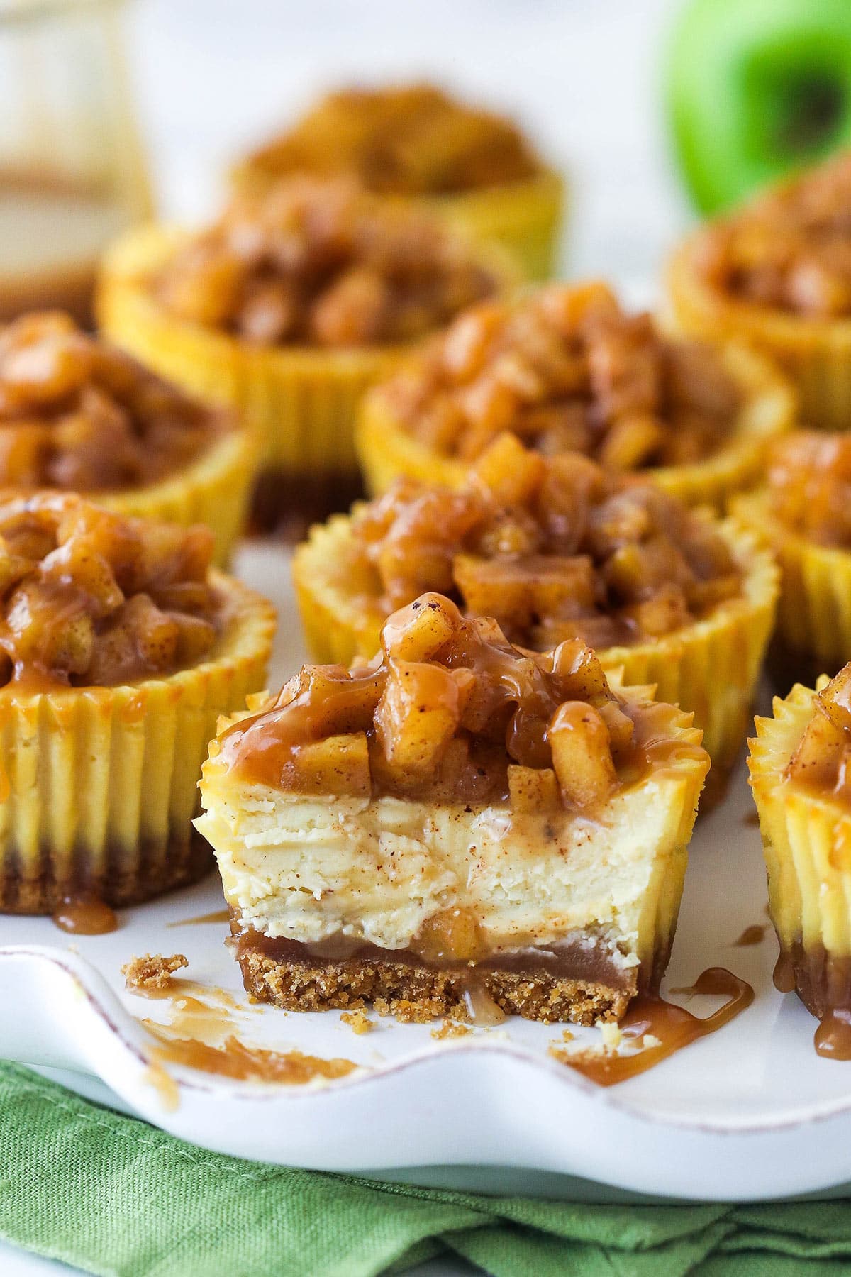 Closeup of a mini caramel apple cheesecake with a bite taken out of it.