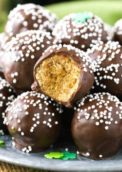 No-bake Baileys cookie balls piled onto a plate with one missing a bite to reveal the cookie inside the chocolate coating