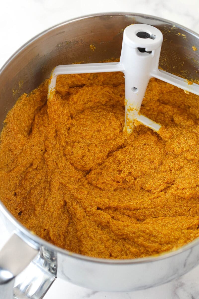 Adding pumpkin puree to wet ingredients for pumpkin loaves.
