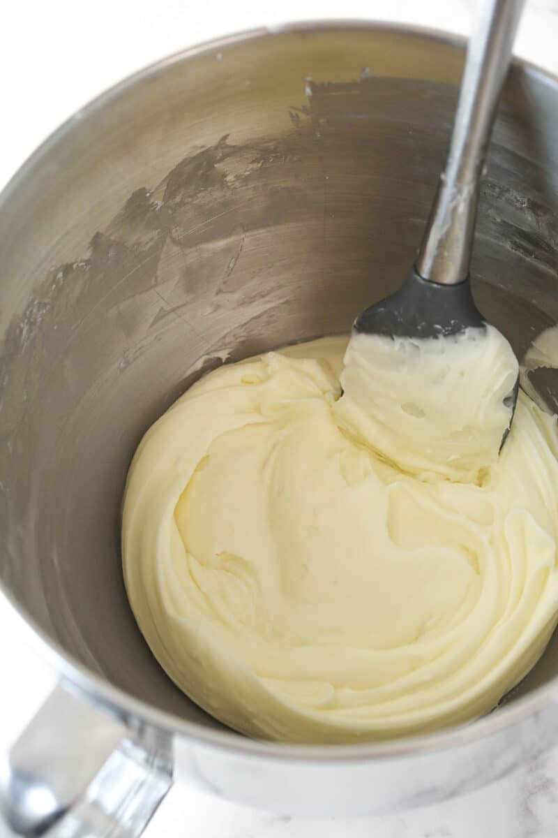 Stirring cream cheese frosting with a rubber spatula.