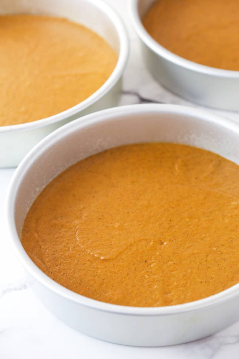 Pumpkin cake batter in 3 cake pans ready to be baked.