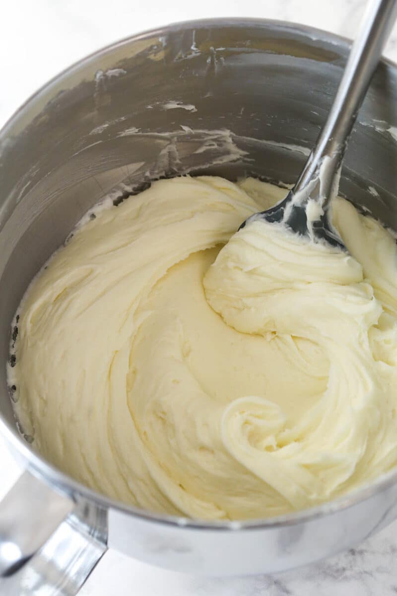 Stirring cream cheese frosting in a mixing bowl.