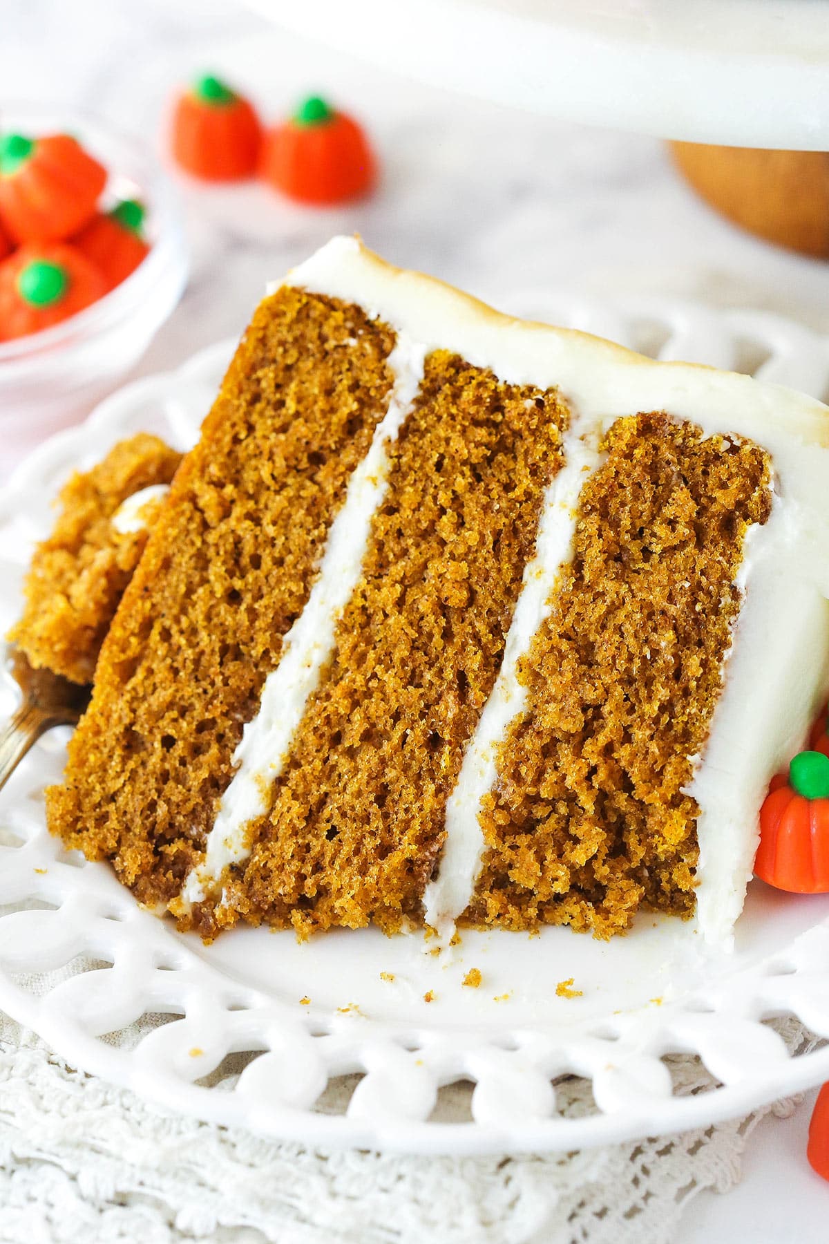 A slice of pumpkin layer cake on a plate with a bite taken out of it.