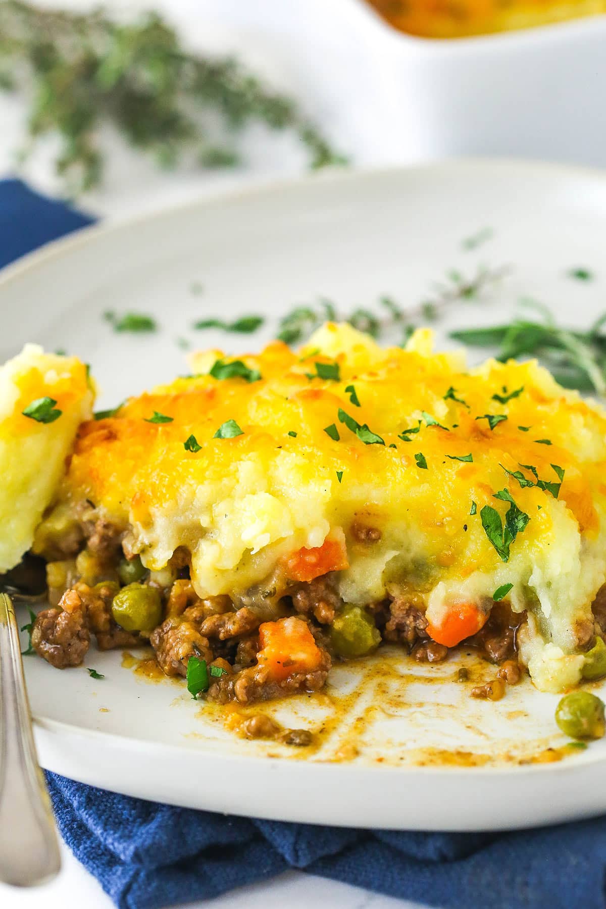 A slice of shepherd's pie on a plate with a bite taken out of it.