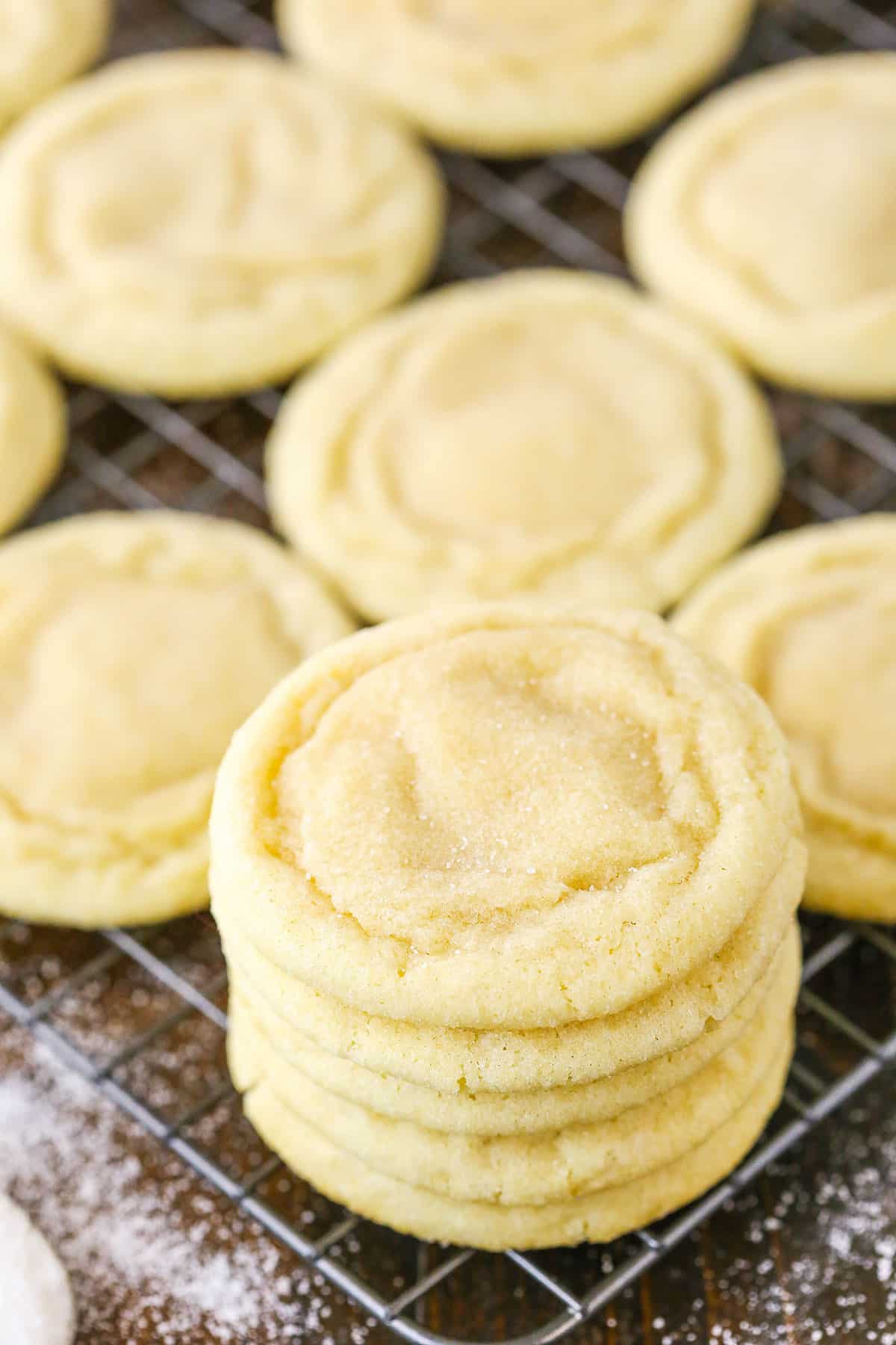 Five Sugar Cookies stacked on top of each other with more Sugar Cookies spread over a cooking rack