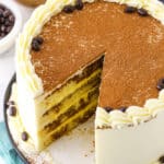 Overhead view of a full Tiramisu Layer Cake with a slice removed on a black plate